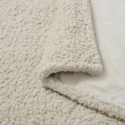 Manta blanca esponjosa, de textura suave y acogedora, cubierta sobre una superficie blanca.