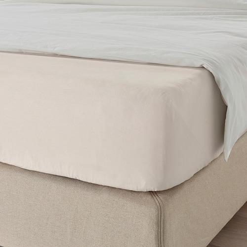 Una cama cuidadosamente hecha con una sábana bajera lisa y de color claro, con bordes elásticos para mayor comodidad y calidad.