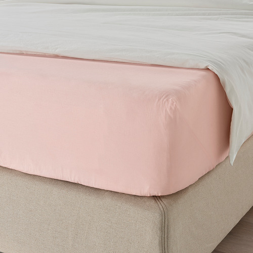 Una cama cuidada con una sábana bajera de color rosa claro que cubre el colchón, mostrando sus bordes elásticos para adaptarse a colchones de hasta 26 cm de grosor.