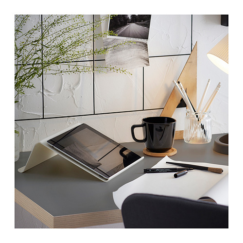 Configuración de escritorio de trabajo con tableta, taza negra, lápices y planta. Diseño limpio y moderno con tablero blanco y patas de madera.