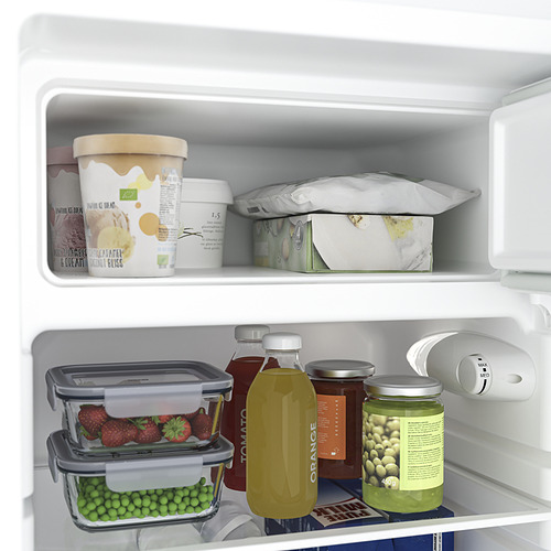 Abra el refrigerador con artículos: fresas, guisantes, jugo y helado. Estantes de vidrio ajustables a la vista.