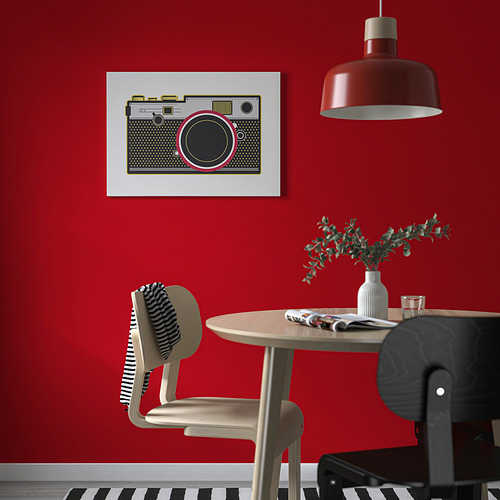 Comedor moderno con pared roja atrevida, arte de cámara retro, mesa redonda y lámpara colgante roja.
