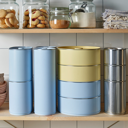 Coloridas latas apiladas para almacenar en el estante con galletas y frascos encima.
