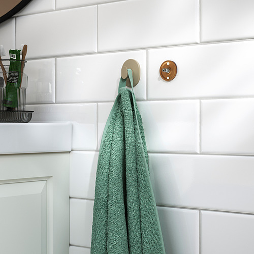 Toalla verde en gancho de pared en el baño