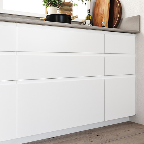 Modernos gabinetes de cocina blancos con diseño minimalista, superficies lisas y manijas integradas; Suelo de madera.