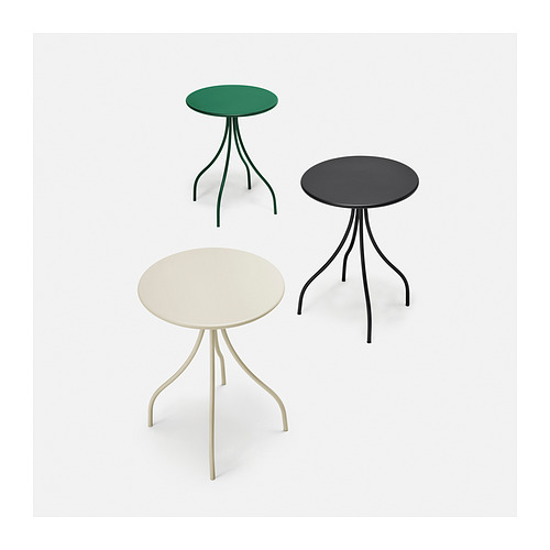 Tres coloridas mesas redondas con patas delgadas y curvas dispuestas en forma triangular; Parte superior verde, parte superior negra, parte inferior beige.