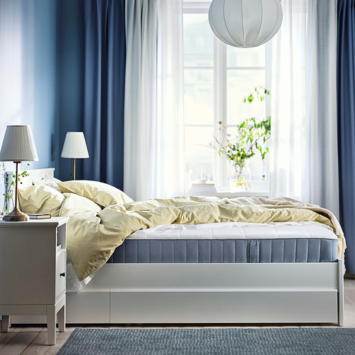 Dormitorio amplio y luminoso con ventana grande, ropa de cama blanca, colchón gris, manta amarilla, lámparas de noche y linterna colgante.