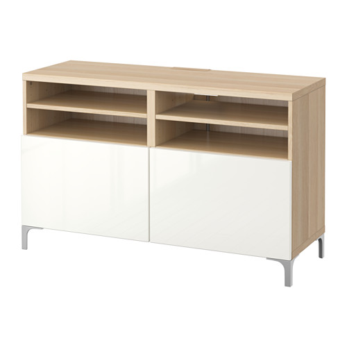 Un banco de televisión BESTÅ de ikea en roble blanco y claro. Tiene estantes abiertos y gabinetes cerrados con un diseño elegante y moderno.