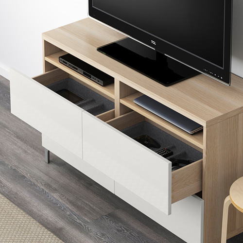 Mueble de tv de madera con cajones abiertos, que sostiene controles remotos y dispositivos electrónicos, que exhiben la organización.