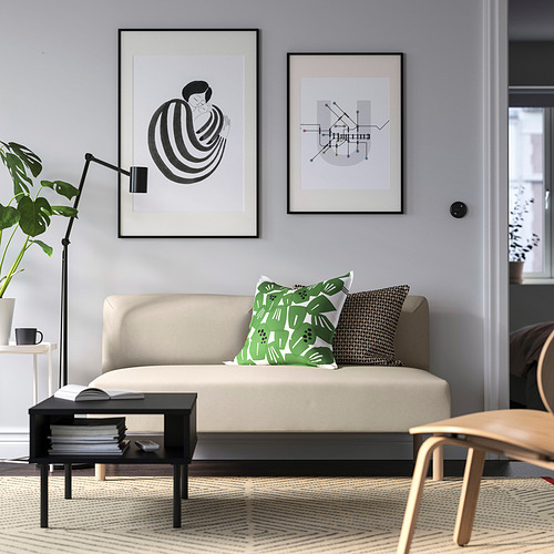 Sala de estar moderna con sofá beige lillem, mesa de centro negra, dos obras de arte enmarcadas y plantas. Cojines de sofá en verde y negro.