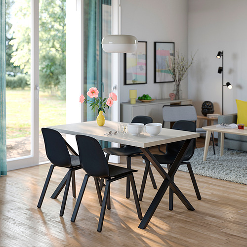 Juego de comedor moderno: mesa blanca SKÅLSTA, sillas negras. Mesa cuadrada, patas angulares. Gran ventanal, habitación luminosa.