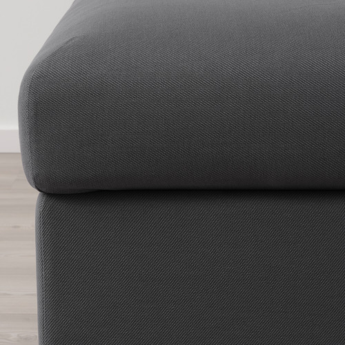 La imagen muestra un primer plano de un sofá suave de color gris oscuro con tela lisa y duradera, resaltando su textura cómoda y de alta calidad.