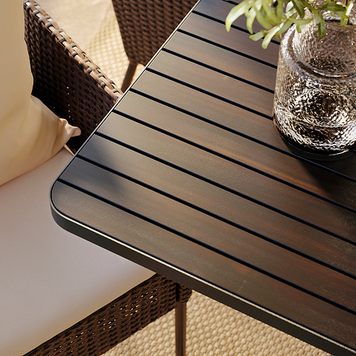 Moderno ambiente al aire libre con elegantes mesas a rayas y sillas de mimbre. Decorado con planta y cojín.