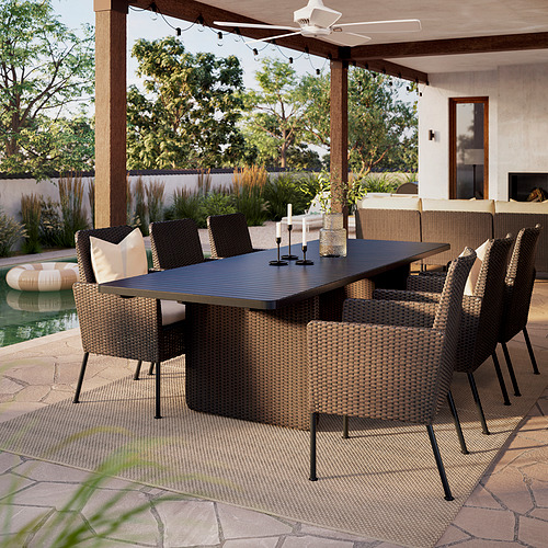 Patio exterior con mesa rectangular VITTSKÄR y sillas de mimbre, colocado bajo una pérgola, rodeado de vegetación y una piscina.