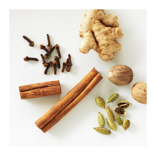 Especias variadas sobre blanco: canela, cardamomo, jengibre, nuez moscada, clavo.