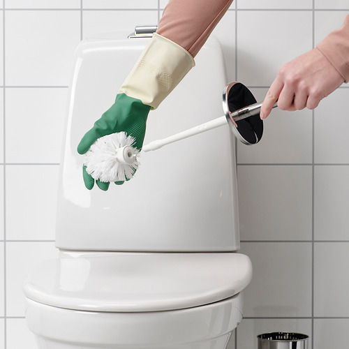 Persona limpiando un inodoro con un cepillo blanco y guantes verdes.