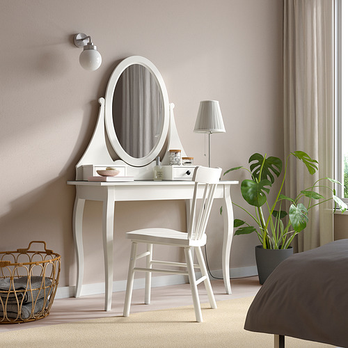 Conjunto de tocador HEMNES con espejo, silla y planta junto a una cama grande