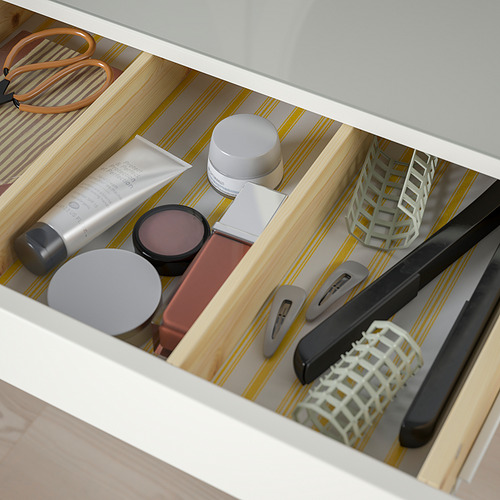 Cajón abierto del tocador HEMNES que muestra cosméticos, herramientas y organizadores, lo que indica un almacenamiento práctico para artículos de belleza.