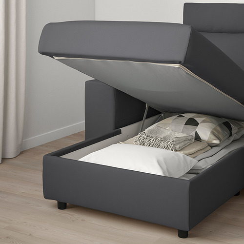 Sofá de tela gris con almacenaje al que se accede por asiento elevable, almohadas en el interior.