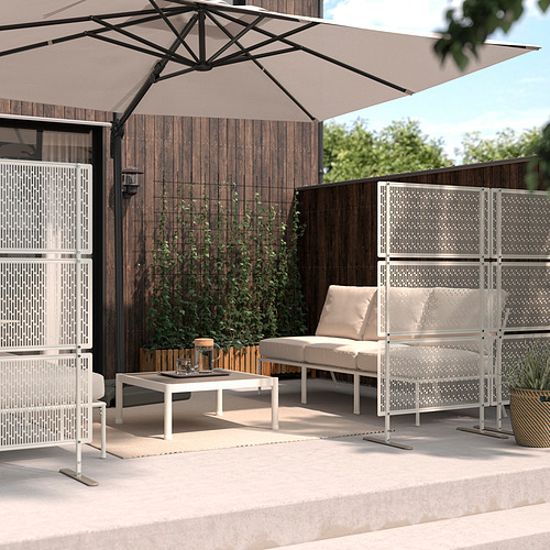 Moderna zona exterior con pantallas de privacidad LUNGÖN beige, muebles blancos y una gran sombrilla. Patio de hormigón, fondo de valla de madera.