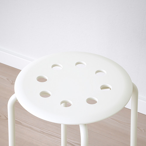 Un elegante taburete blanco con cuatro aberturas redondas, que descansa sobre un suelo de madera. Diseño minimalista, calidad de construcción robusta.
