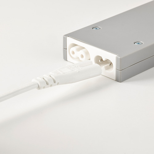 Un adaptador de corriente plateado conectado a un enchufe y un cable blancos, que se utiliza para la conexión de la lámpara de red con control inalámbrico.