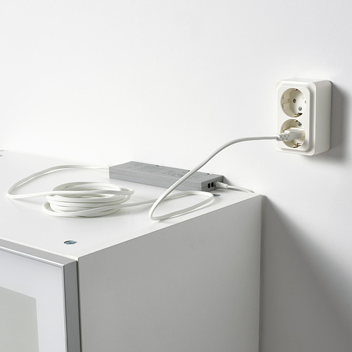 Adaptador de corriente blanco enchufado a la toma de corriente, que suministra energía a las tiras de led para la iluminación.