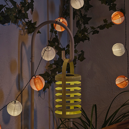 Una luz decorativa de exterior SOLVINDEN con múltiples farolillos, alimentados por energía solar, que arrojan una luz cálida por la noche.