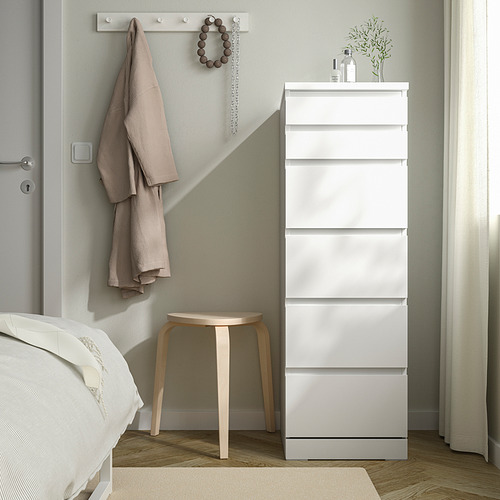 Dormitorio moderno con tocador MALM blanco, toallas, collar, taburete de madera, cama, cortina.