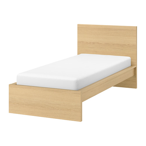 Una cama MALM en roble claro con colchón blanco, diseño sencillo, cabecero de madera.