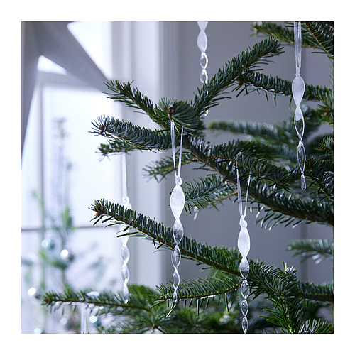 Ligeros adornos de carámbanos plateados cuelgan de un pino. Decoradas con vidrio brillante, cada una tiene un diseño retorcido.