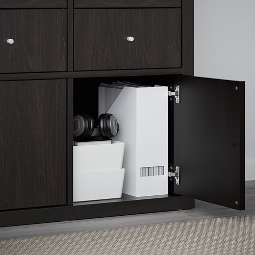 Estante KALLAX negro con puerta abierta, que muestra almacenamiento organizado que incluye cajas blancas y auriculares negros.