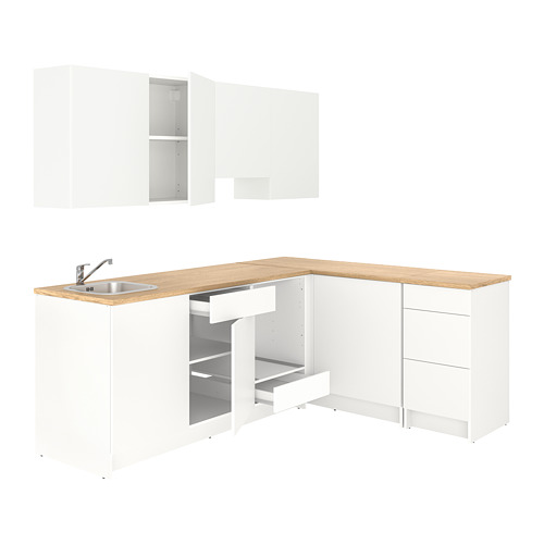 Un conjunto de cocina de esquina blanco compacto y moderno con encimeras de madera clara, con cajones y gabinetes abiertos.