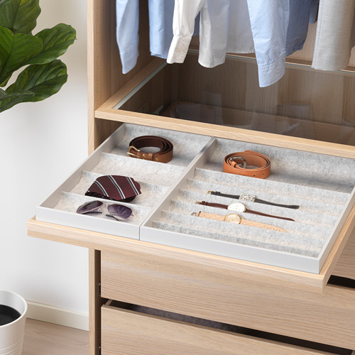 El cajón de madera con compartimentos organiza accesorios como cinturones, corbatas y relojes en un armario.