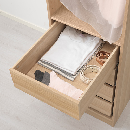Cajón abierto de madera con ropa y accesorios doblados, parte del sistema de almacenamiento KOMPLEMENT de ikea.