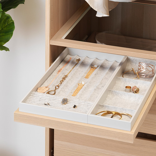 Cajón de madera abierto con bandeja de joyería que muestra collares, anillos y pendientes.