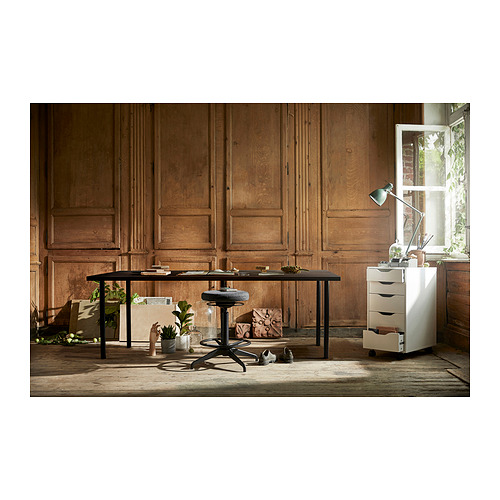 Escritorio LAGKAPTEN, tapa negra, patas de metal, cerca de la pared y ventana de madera, con silla, gabinete y plantas.