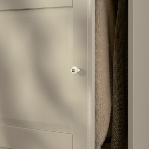 Puerta de armario blanca con bordes de panel redondeados, con bisagra de cierre suave para un cierre suave y silencioso, colocada junto a textiles grises plegados.