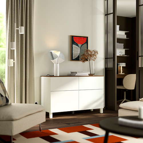 Sala de estar moderna con aparador blanco BESTÅ , lámpara geométrica, arte abstracto, cortinas blancas y alfombra estampada.