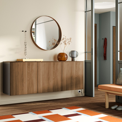 Pasillo moderno con aparador BESTÅ en madera clara. Espejo circular, jarrones, alfombra naranja, banco. El amplio gabinete se adapta a la pared, enfatizando el espacio y la decoración.