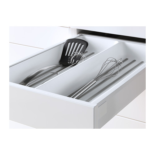 Cajón de cocina blanco con utensilios: espátula, batidor, pinzas, cuidadosamente organizados.