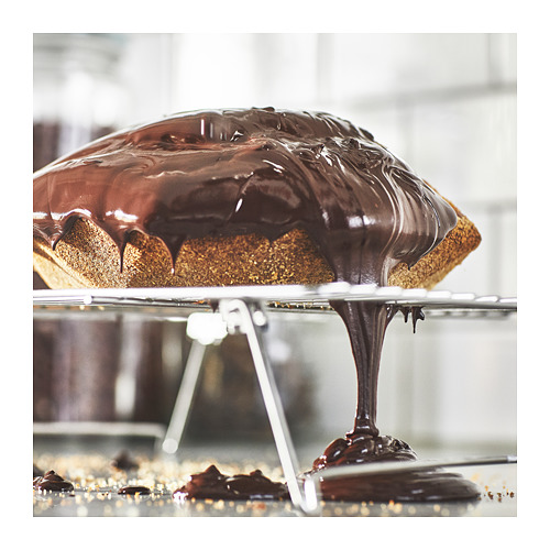 Pastel de chocolate cuadrado sobre una rejilla de enfriamiento de alambre con glaseado brillante goteando por los lados.