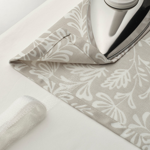 La cortina con patrón floral está cubierta sobre hierro. Cinta de encabezado visible para opciones de colgado de varillas o rieles.