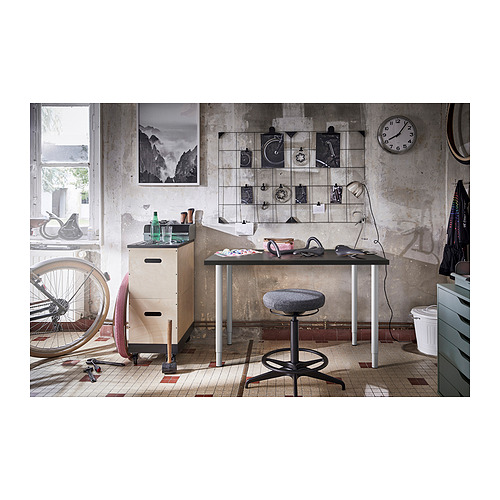 Espacio de trabajo de estilo industrial con escritorio y taburete ajustables, bicicleta metálica.