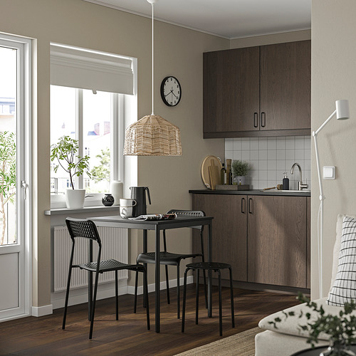 Cocina moderna con sillas negras sandberg, elegantes gabinetes de madera oscura, encimera blanca, lámpara colgante y reloj.