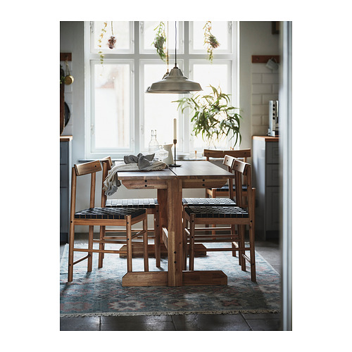Acogedor juego de comedor con mesa de madera y sillas de mimbre junto a la ventana.