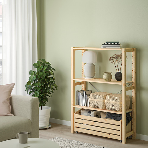Sala de estar verde claro con estante IVAR de madera clara, lámpara blanca, plantas y cojines.