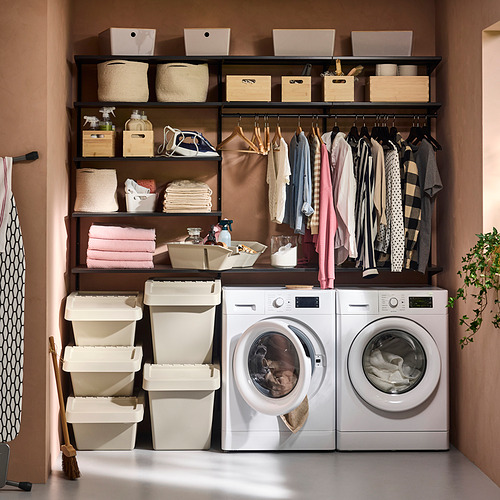 Lavandería organizada con lavadoras, contenedores de almacenamiento clasificados, ropa colgada y artículos de limpieza en estantes.