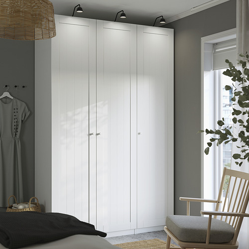 Dormitorio moderno con un gran armario blanco GULLABERG y una silla de madera cerca de la ventana.