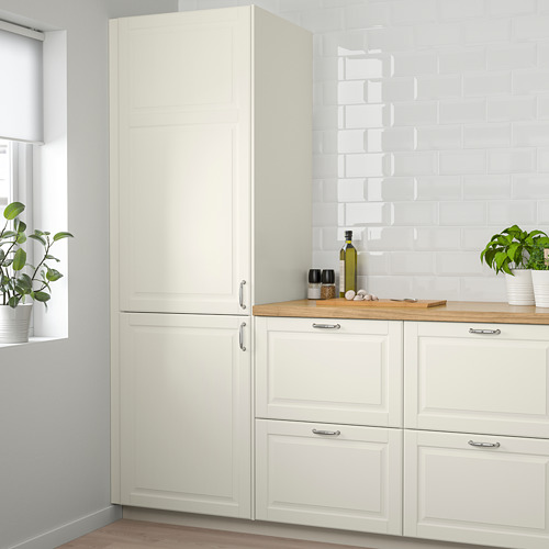 Mueble BODBYN blanco roto de diseño clásico, nevera alta, encimera de madera y planta.